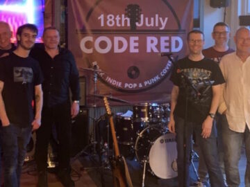 The 6 members of Code Red band posing either side of their instruments who are at the Club 18th July 2026